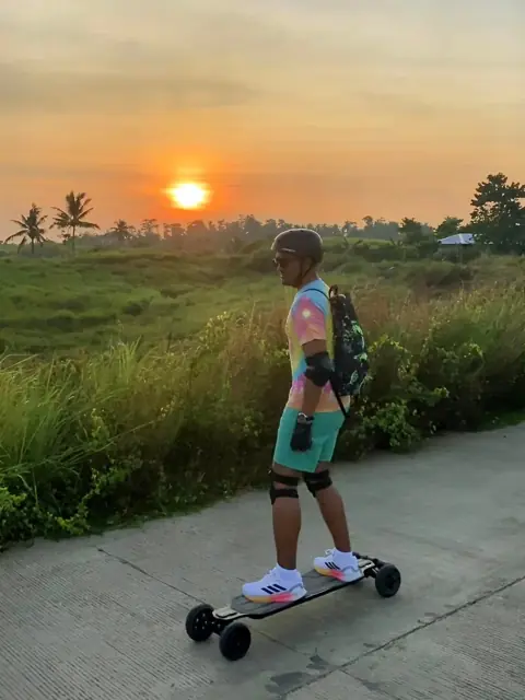 Merald longboarding on a country road at sunset