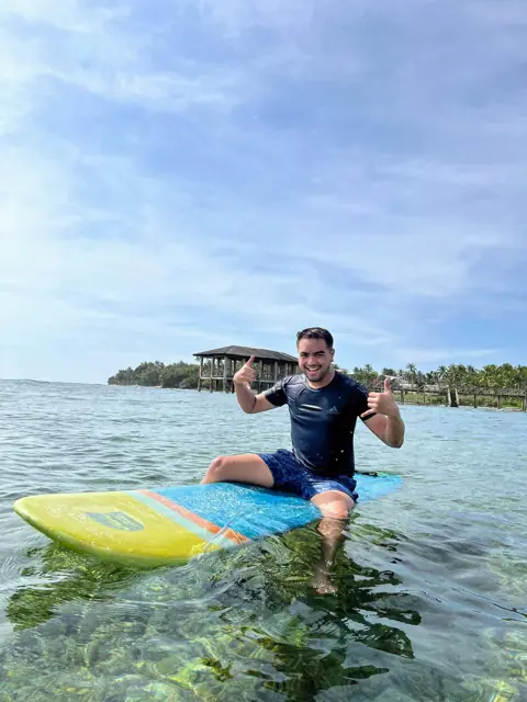 Merald sitting on a paddleboard in clear shallow water