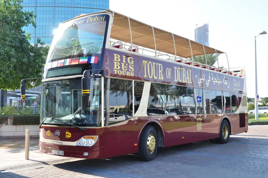 An open-top sightseeing tour bus parked on a sunny city street