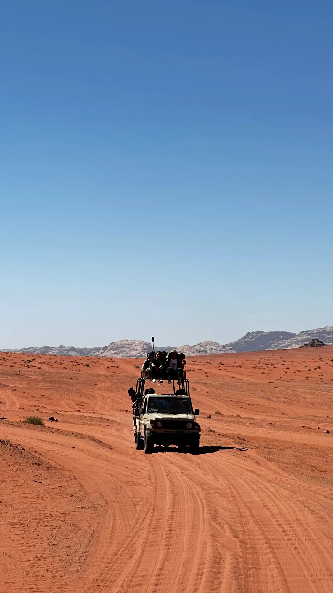 A 4x4 jeep carrying travellers across the red sand of Wadi Rum desert in Jordan
