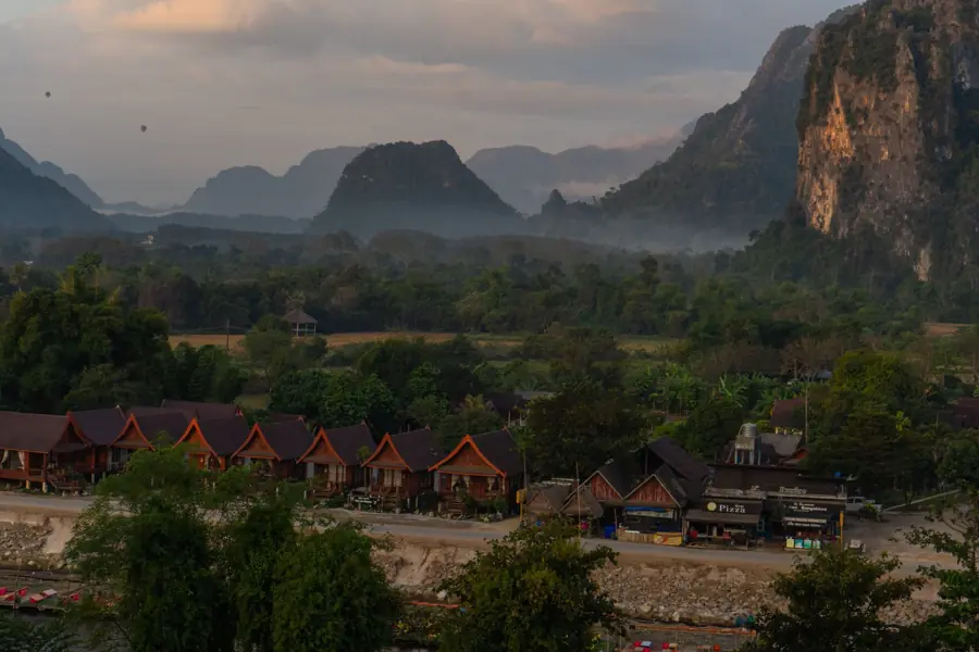 Mist over the limestone karsts and huts of Vang Vieng, Laos.