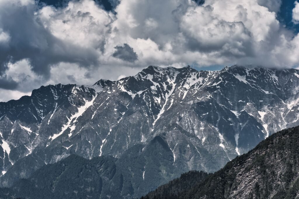 Breathtaking view of the snow-capped Himalayas under a dramatic cloudy sky in Uttarkashi, India.