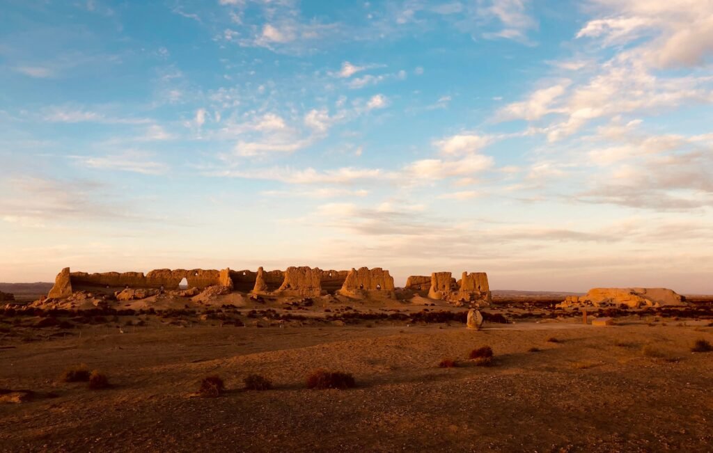 Ancient Hecang Fortress ruins in the Gobi Desert, Gansu, China under a dramatic blue sky.