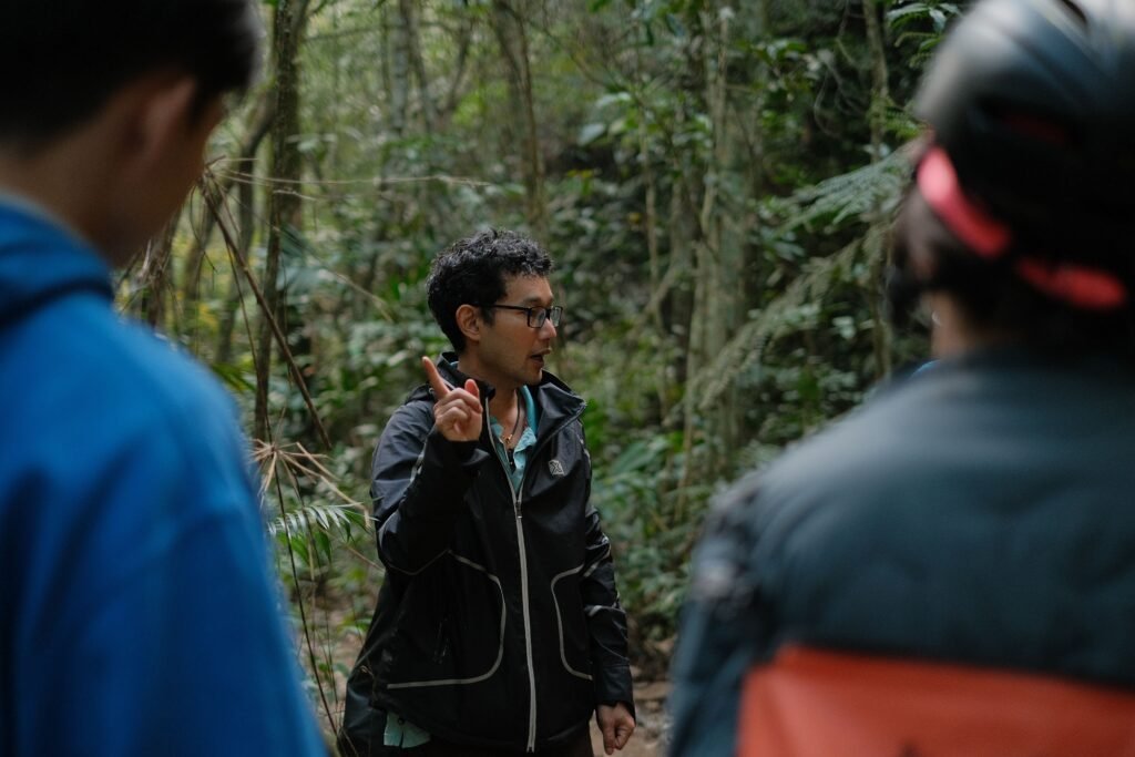 A guide leading a group of people on an informative nature walk in a dense forest.