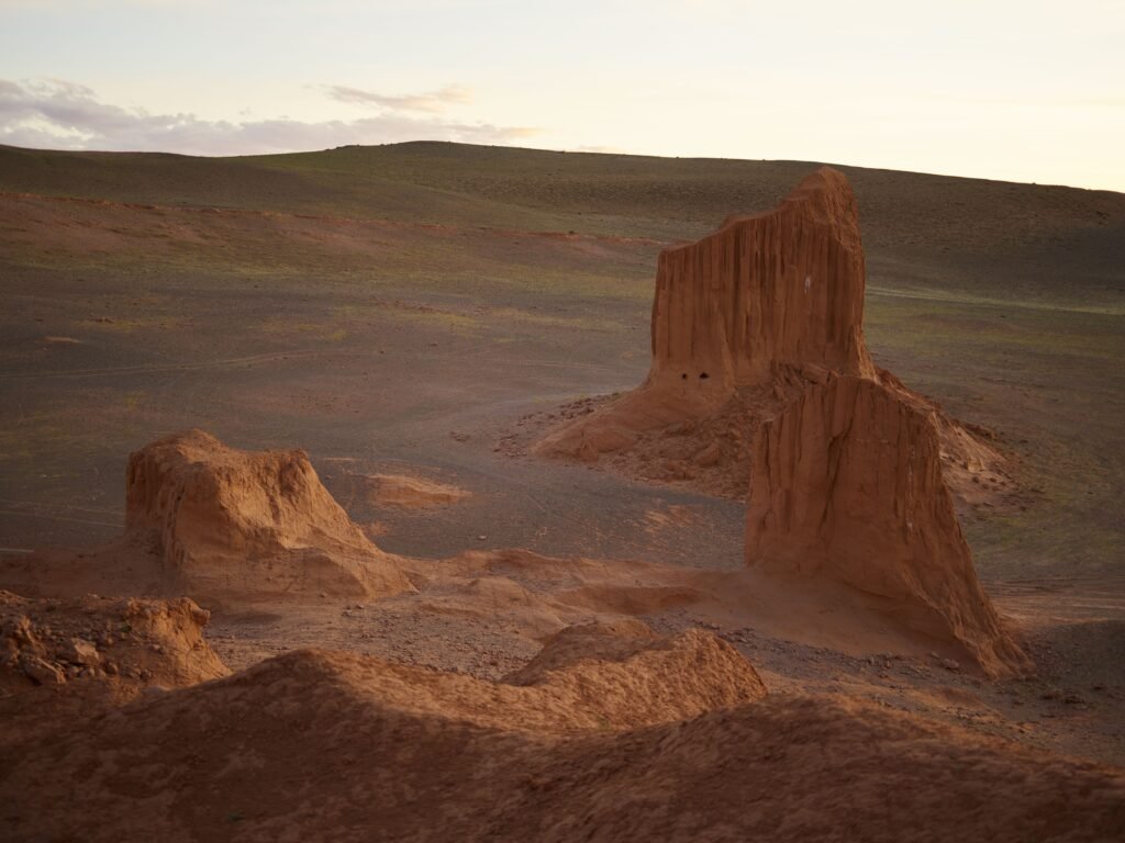 Majestic aerial view of red cliffs in empty desert valley under bright sky in coming evening